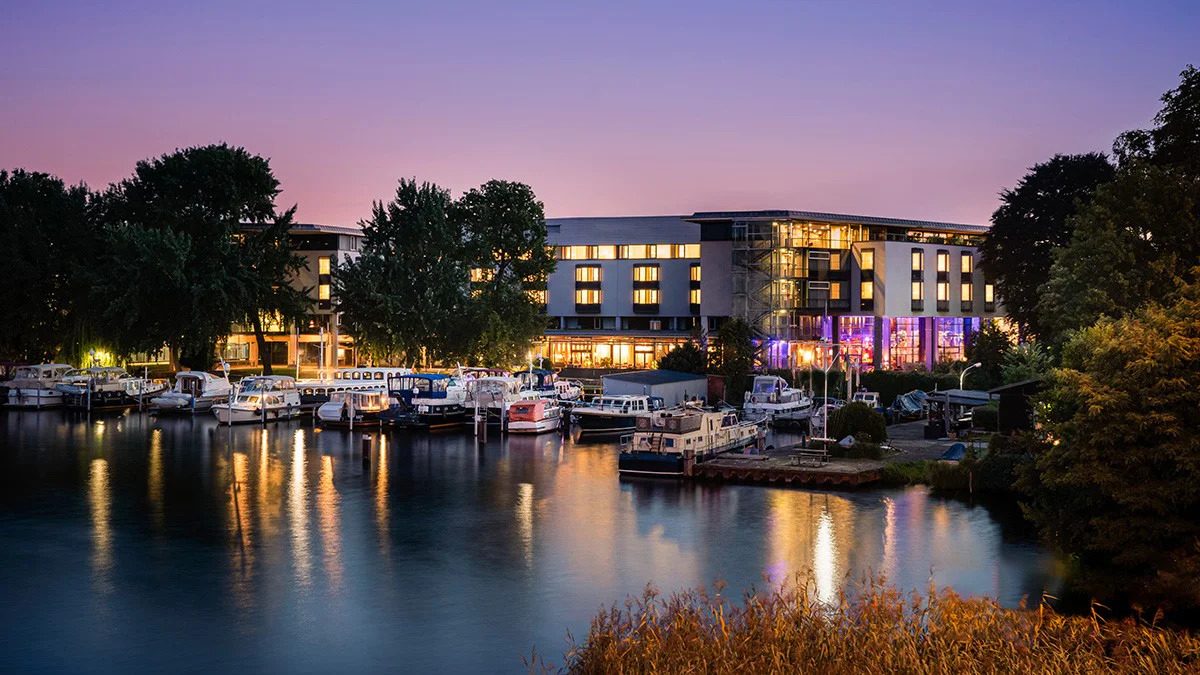 Der Spree Marine Hafen am Abend mit beleuchteten Booten und Hotel im Hintergrund
